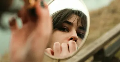 Pourquoi je rougis tout le temps et comment arrêter - femme qui se regarde dans un petit miroir