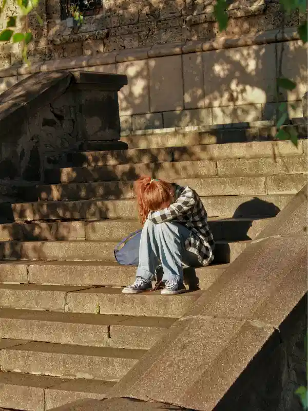 Femme seule sur des escaliers illustrant l'isolement et la souffrance liés à l'anxiété et au stress