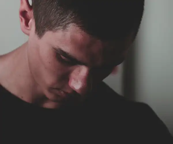Homme tête baissée, regard vers le sol, expression de repli sur soi