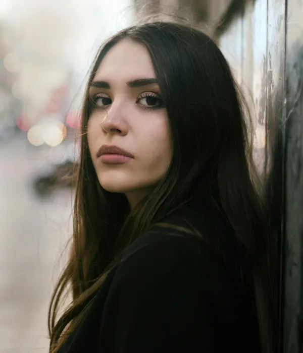 Femme pensive regardant au loin, symbolisant le doute et le manque de confiance en soi mais qui est décidée à changer