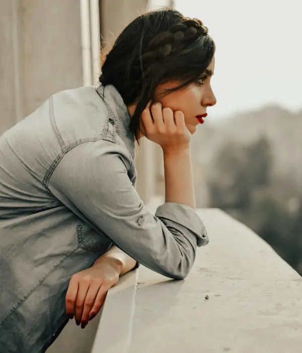 Femme pensive regardant au loin, symbolisant le doute et le manque de confiance en soi, la souffrance engendrée