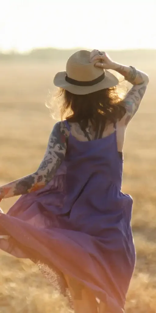 Femme de dos dansant librement dans un champ au coucher du soleil, symbolisant la liberté d'agir retrouvée